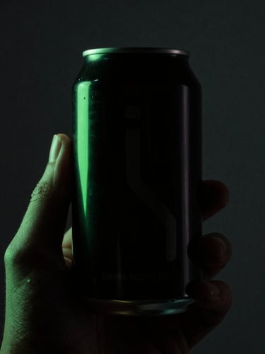 Extreme close-up of a hand holding a sleek black functional beverage can, dramatic high-contrast studio lighting, electric green light outlining the silhouette, dark charcoal backdrop, 35mm photography