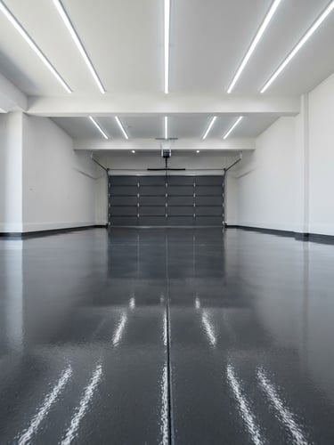 High-gloss finished epoxy garage floor, dark grey, with perfect reflections of overhead lights, clean and empty, architectural photography style, bright high-key daylight, wide-angle low perspective, high contrast cool tones, pristine condition, no people.