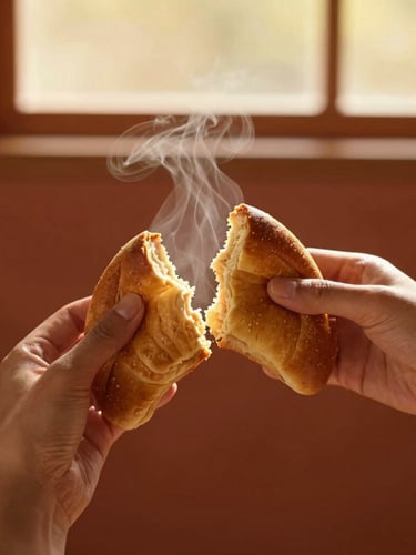 A portrait-oriented, warm editorial photograph of a golden-brown sheca being gently torn in half by hand, steam rising from the soft interior, rich terracotta background, shallow depth of field, 35mm