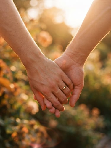 Close-up of a couple holding hands, fingers intertwined, warm golden-hour sunlight filtering through, soft sun flares, rich terracotta tones, candid 35mm film style