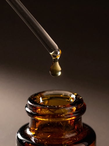 Macro photograph of a thick amber attar droplet suspending from a glass rod over a dark crystal bottle, low-key chiaroscuro lighting, deep shadows, gold highlights.