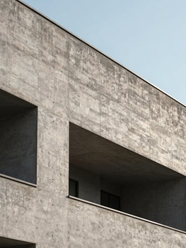 Minimalist architectural photograph of a brutalist concrete building facade, sharp geometric shadows cast by direct afternoon sun, high contrast, clean sky background