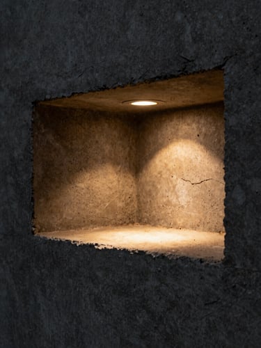 Extreme macro detail of a hidden light recess carved into raw monolithic concrete, dramatic side-lighting, deep shadows, warm amber highlights, 35mm lens