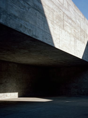 Ultra-wide shot of a monolithic concrete structure under dramatic low-angle sunlight, sharp interior angles, high-contrast light and shadow, empty architectural space, obsidian and concrete tones, 35mm film.