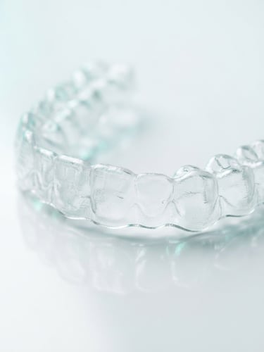 Macro studio photography of a crystal-clear medical polyurethane dental aligner, bright clinical lighting, clean white background with subtle medical teal reflections.