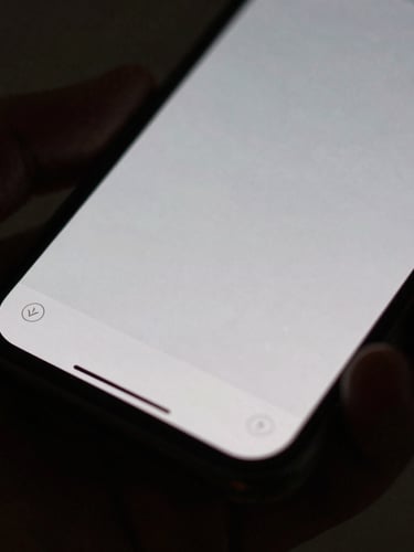 Macro close-up of a hand holding a smartphone showing a minimalist grid layout, soft side-light, deep shadows