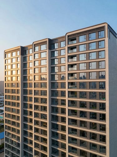 Wide panoramic drone shot of a completed luxury residential tower facade, golden-hour light raking across geometric concrete and glass panels, deep shadows emphasizing structural precision, empty sky on the upper third, building filling the right two-thirds of the frame