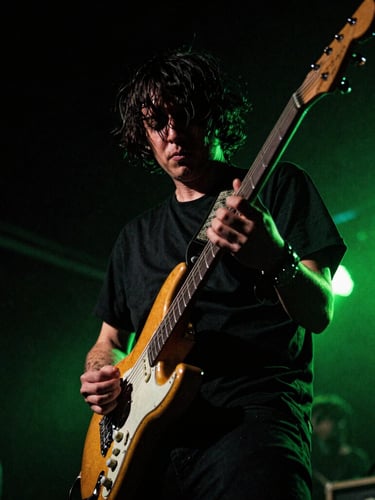 Gritty high-contrast music photography, a guitarist on a dark concert stage with neon green lighting flares, 35mm film grain, close-up dynamic angle