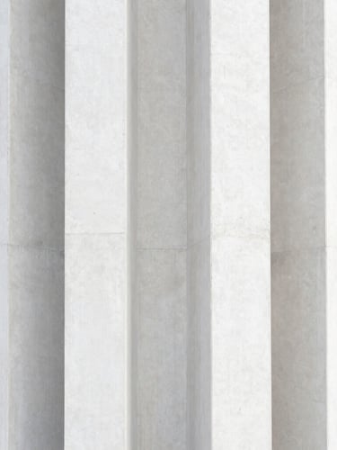 Symmetrical close-up of structural concrete columns under diffused daylight, sharp architectural lines, premium texture