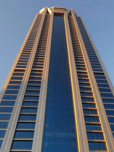 Low-angle heroic shot of a modern skyscraper facade in Riyadh under crisp golden hour sunlight, highlighting heavy steel and glass structural lines, editorial architectural photography, 35mm lens