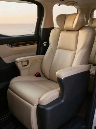 Close-up of Toyota Alphard interior, ivory and dark charcoal leather ottoman seat fully reclined, diffuse golden-hour light filtering through frosted rear window, polished grab handle in sharp focus, deep calm atmosphere, no passengers