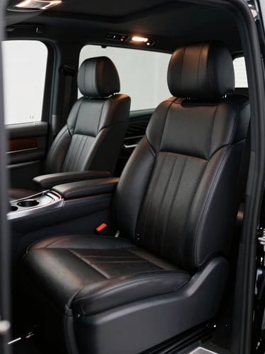 Close-up of Mercedes-Benz V-Class interior, butter-soft black leather captain's chairs, polished dark wood console, cool ambient cabin lighting, door panel detail in foreground, deep shadow framing the composition, no passengers