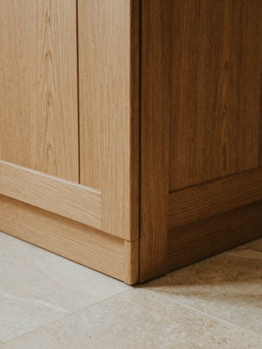 Close-up of grain-matched oak paneling meeting a honed limestone floor, perfect joinery, warm architectural photography, natural side-lighting