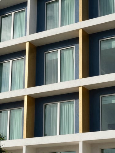 Architectural detail of a modern, sunlit building facade in Hobe Sound, Florida. Clean lines, natural coastal window light, deep navy and warm gold accents. Sharp focus, wide shot.