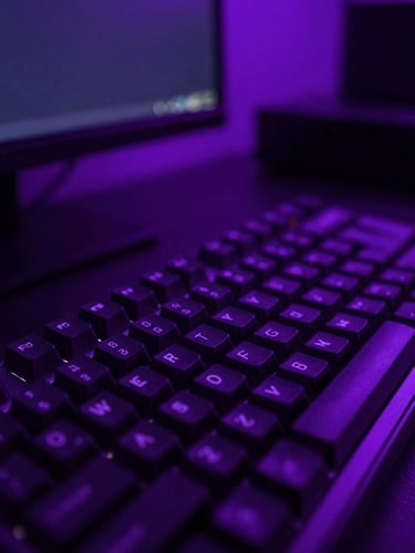 Stylized neon-lit creator workspace, macro close-up of mechanical keyboard and dual monitors glowing with deep violet and purple light, high-contrast obsidian tones, 35mm