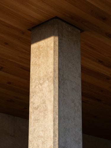 Vertical portrait of a concrete structural column meeting a polished oak ceiling, dramatic side lighting highlighting the rich textures, 35mm architectural photography