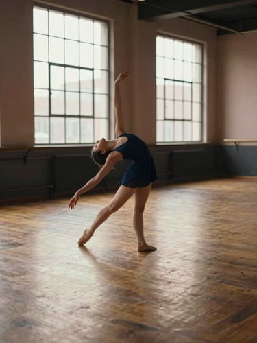 A warm, sunlit dance studio with polished wood floors, large industrial windows casting soft natural side-light, and a single dancer stretching gracefully.