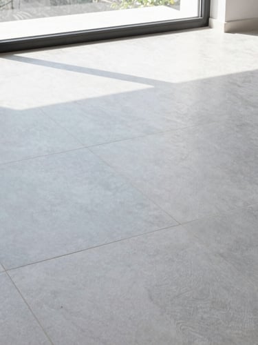Low-angle architectural shot of a modern living room floor with large format light gray porcelain tiles, bright natural daylight streaming through a window, clean slate blue tones, sharp focus, 35mm