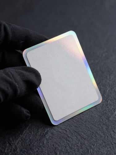 Macro shot of a pristine vintage holographic card corner held in a black microfiber-gloved hand under cold-toned studio rim lighting, dark slate background.