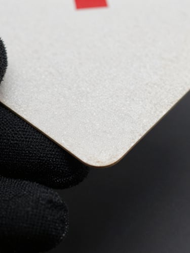 Macro close-up of a pristine vintage card corner held by a hand in a black microfiber glove, sharp cool-toned rim light highlighting the card edge.