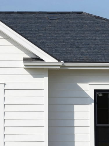 Crisp architectural photograph of a completed modern home exterior with clean siding lines and a new dark shingle roof under bright daylight.