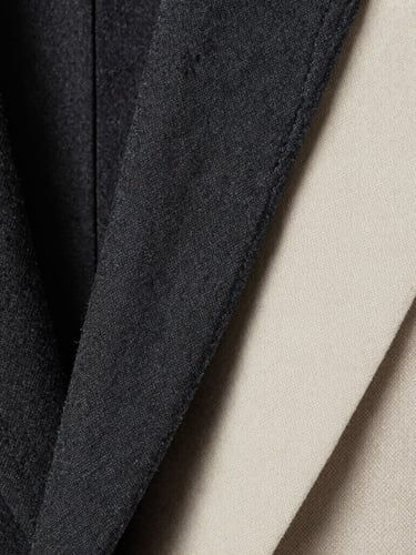 Close-up macro shot of high-quality charcoal wool textile and precise double-stitching on a blazer lapel, high-contrast studio lighting, sharp focus, 35mm lens