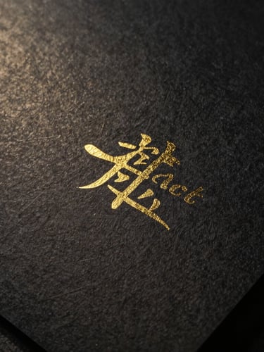 Macro detail of high-end textured black paper with gold foil debossing, dramatic side lighting, 35mm photography