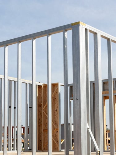 Meticulous detail shot of a luxury home under construction, showing clean structural steel framing and exposed timber joints, bright natural light, architectural precision, 35mm.