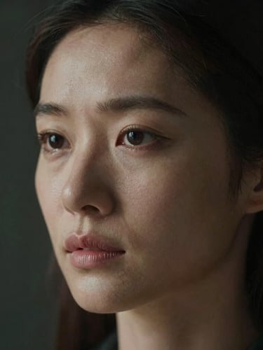 Extreme close-up portrait of a woman in low-key side lighting, unretouched skin, thoughtful expression, dark background