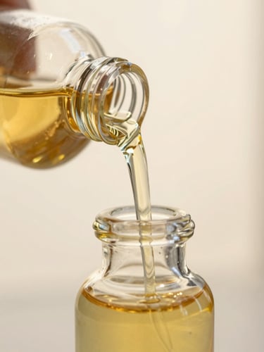 Premium close-up of thick golden attar oil pouring into a heavy crystal bottle, soft morning light, shallow depth of field, 35mm