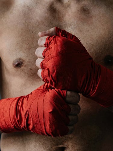 Close-up of an athlete's hands tightly wrapping in red cotton wraps before a fight, gritty side lighting, deep shadows, raw texture