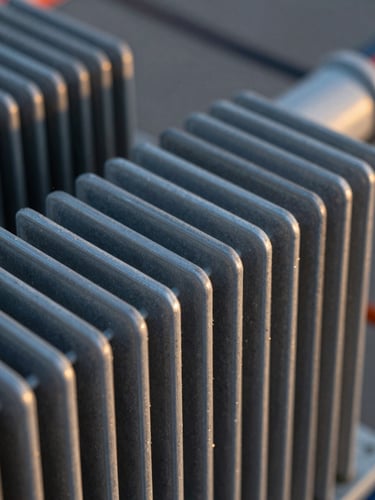 Macro close-up of a high-voltage transformer cooling fin coated with advanced passive polymer, intense metallic texture, high-contrast twilight lighting