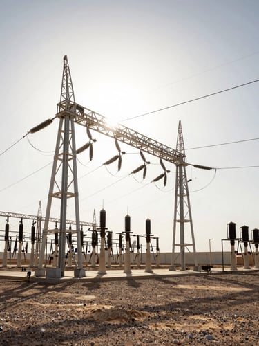 Wide-angle cinematic shot of a massive electrical substation in the MENA desert under a harsh, high-contrast midday sun, deep shadows, heat shimmer rising from the ground, ultra-precise composition.