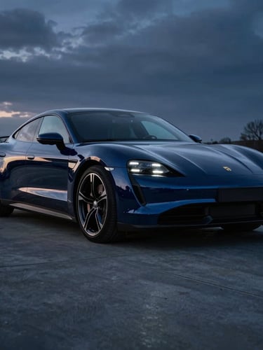 Low-angle heroic shot of a polished modern electric sports car parked on a sleek dark concrete driveway in Vottem, dramatic twilight lighting, deep midnight blue reflections on the flawless paint, sharp cold-toned highlights emphasizing the vehicle's curves, high contrast, 50mm lens.
