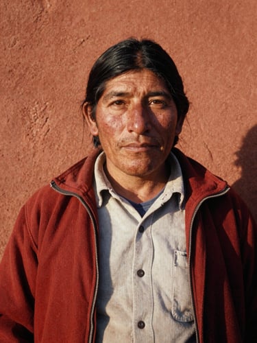 Portrait of a Bolivian community leader in warm golden-hour light, proud expression, rich terracotta tones, authentic documentary photography, 35mm film texture