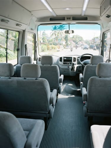 Wide-angle interior shot of a clean, spacious Isuzu ELF microbus cabin, bright Indonesian daylight streaming through windows, plush grey seats, immaculate dashboard, 35mm lens