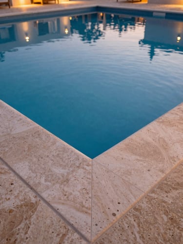 Close-up of a knife-edge pool overflow at twilight, water perfectly level with the surrounding travertine deck, architectural lighting, wide-angle lens, 35mm