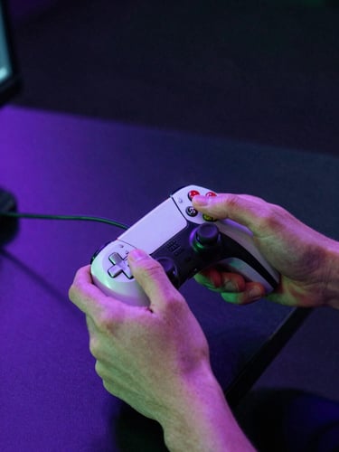 Close-up of a competitor's hands gripping a gaming controller mid-match, arena stage lighting casting electric violet and neon green hues across the frame, dark background with high-contrast broadcast glow, intense focused energy