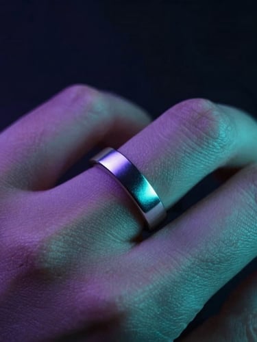 Tight macro shot of a hand in motion, metallic reflections of a seamless silver smart ring catching sharp violet and teal light, dark background