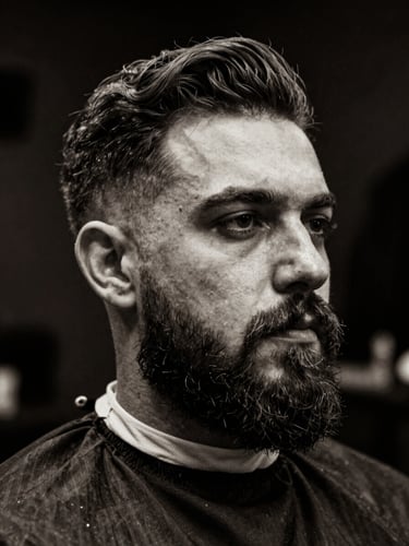 Black and white portrait of a master barber with a neat beard, low-key editorial photography, dramatic side-lighting