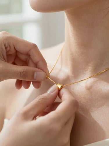 Extreme close-up of a jeweler's hands adjusting an unbroken gold necklace on a model's neckline, soft natural window light, warm gold tones, shallow depth of field, macro
