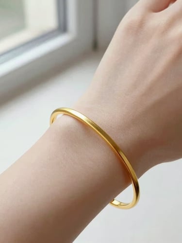 Elegant close-up of a continuous gold bracelet on a wrist, soft natural window light, bright high-key editorial aesthetic