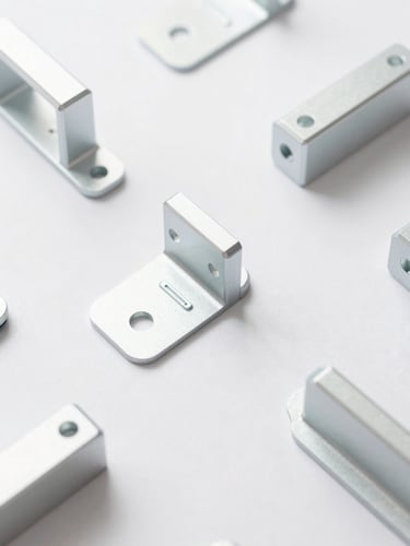 Overhead flat-lay photography of clean, millimeter-precise custom machined aluminum brackets on a high-key pastel background, soft diffused daylight, 50mm