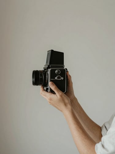 A quiet, natural-light portrait of a photographer holding a vintage medium format camera, soft diffused side light, muted neutral tones, minimalist background