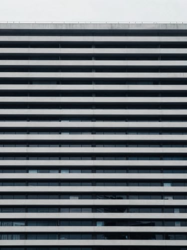 Symmetrical straight-on eye-level architectural photograph of a modern civic building with clean horizontal lines, cool diffused daylight, desaturated navy and gray tones, sharp focus