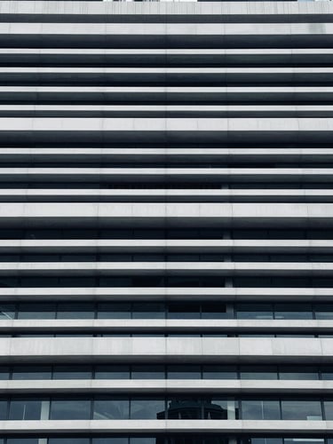 Close-up of structured legal documents and architectural lines of a modern civic building, cool diffused daylight, desaturated navy tones.