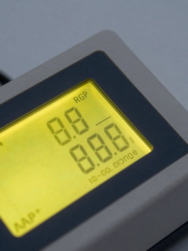 High-contrast close-up of a digital ATP luminometer displaying numerical data, sharp focus on the illuminated safety-yellow screen, slate grey background.