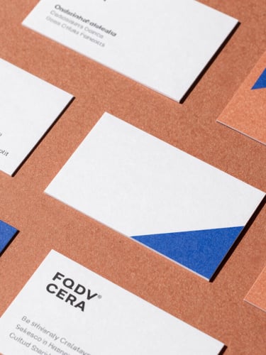 A flat-lay of modern printed brand collateral on textured terracotta paper, featuring clean geometric business cards and packaging under bright Melbourne daylight.