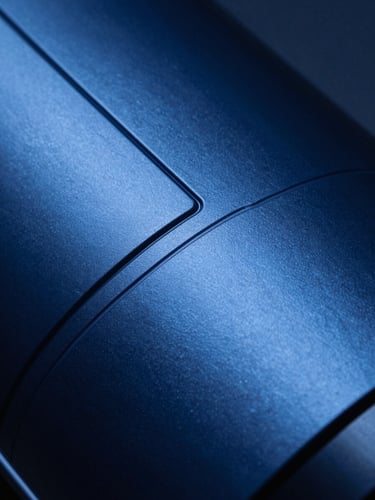 Extreme close-up of a sleek, high-contrast matte metallic surface with precise laser-etched geometric lines, cool sapphire blue studio lighting.