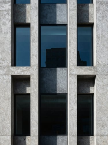 Symmetrical architectural detail of a concrete and glass facade, sharp geometric shadows, cool blue studio lighting, minimal composition.